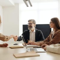 people shaking hands around office table